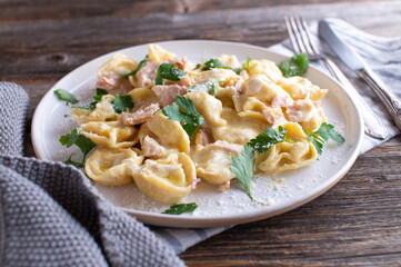 Plate with italian pasta dish. Tortellini with ham, parmesan cheese and parsley in a delicious cream sauce