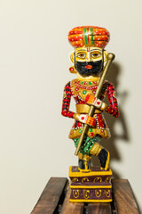 Handmade colorful wooden Rajasthani Doorkeeper or guard souvenir standing with plain background.