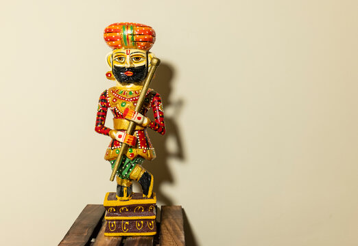 Handmade colorful wooden Rajasthani Doorkeeper or guard souvenir standing with plain background.