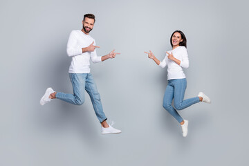 Fototapeta na wymiar Full body photo of cute young brunet couple jump index wear white shirt jeans footwear isolated on grey background