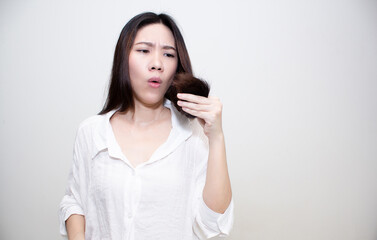 Asian Beautiful woman are looking at hair tip with worry about hair split and dry problem