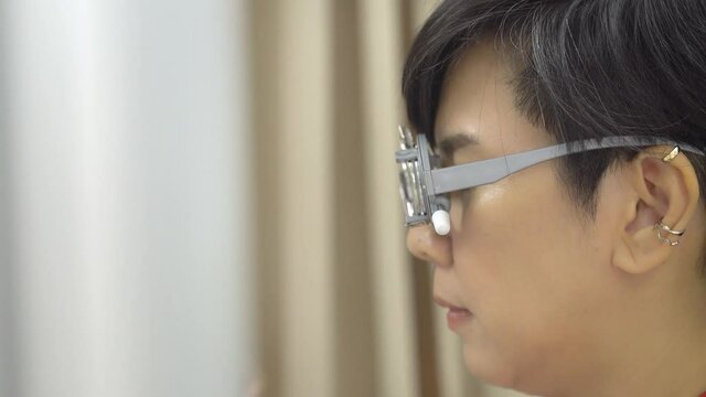 Close up of middle aged Asian woman's face wear eyesight test glasses and optometrist's hand changing optical lens. Eyesight, vision problems and eye care.