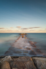 Coastal breakwater overflow with water during high tide at sunset