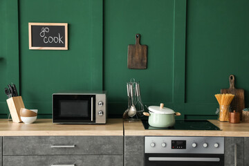 Interior of stylish kitchen with green wall