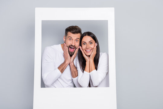 Portrait of attractive stunned cheerful couple having fun in photo frame news reaction isolated over grey pastel color background