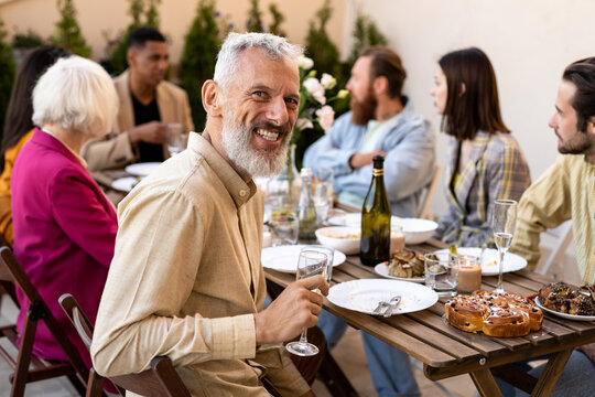 Family and friends celebrating at dinner on a rooftop terrace. Storytelling footage of a multiethnic group of people dining on a rooftop. Family and friends make a reunion at home