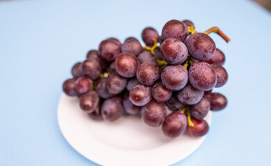 Ripe blue grape berries cluster on plate standing on table