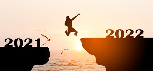 silhouette of person jump from 2021 to 2022 at sunrise with  birds flying and sky background, Concept better future and happy new year 2022 