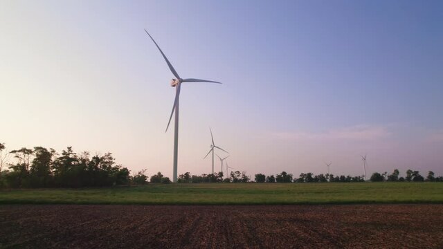 Windmills in a plowed field. Wind farm with turbine cables for wind energy. Renewable energy source, earth care. Drone video of wind power station, 4k. Botiyevska Ves, Ukraine.