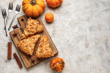 Wooden board with pieces of tasty pumpkin pie on grey background