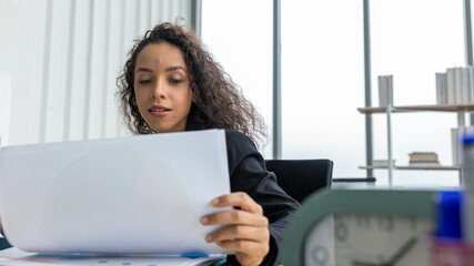 Young economist or accountant is reading result report from her business performance in an office....