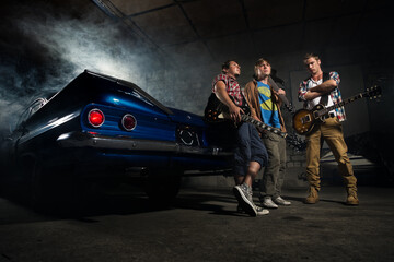 Guitarists at a garage next to the retro car in smoke