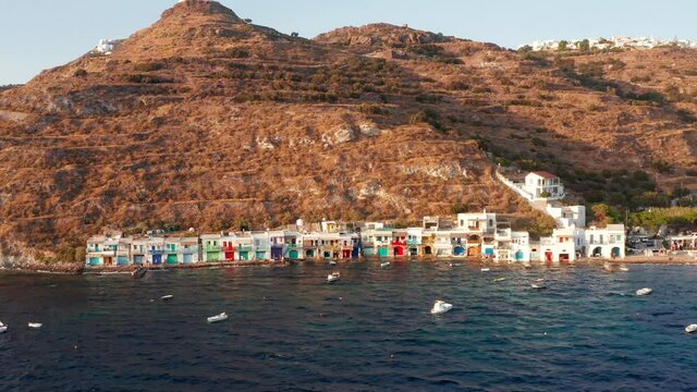 Klima beach with colourful seaside village in Milos island lateral side pan shot