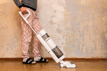 A woman is hoovering floor with stylish vacuum cleaner with dry and wet cleaning functions