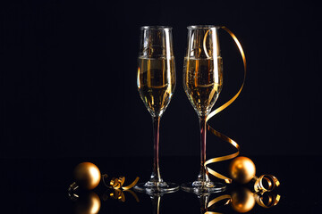 Glasses of champagne and Christmas decorations on dark background