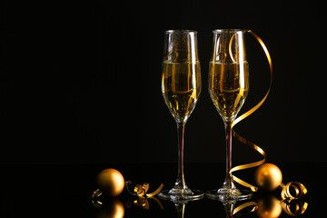 Glasses of champagne and Christmas decorations on dark background