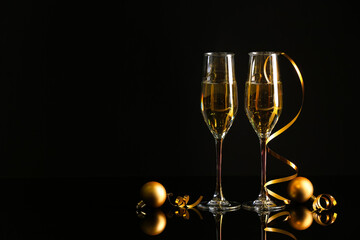 Glasses with champagne and Christmas decorations on dark background