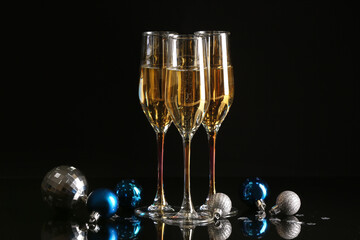 Glasses with champagne and Christmas decorations on dark background