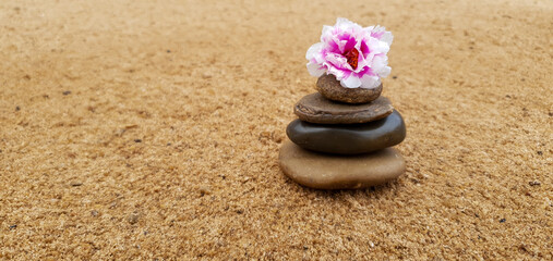 Fototapeta na wymiar stone pyramid with flower in the sand