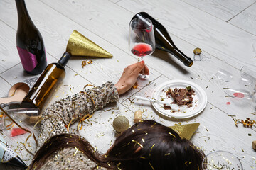Drunk young woman with wine glass lying on floor after party