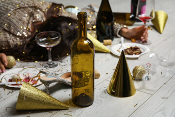 Empty bottle of wine near drunk woman lying on floor after party