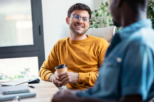 Two graphic designer taking a break while talking and having fun together in modern startup office.