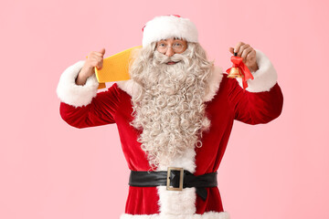 Santa Claus with Christmas bell and skateboard on pink background