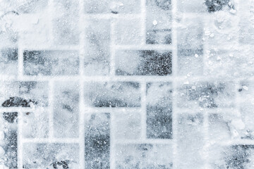 Top aboe overhead view of stone slab tiled pavement covered with snow cold winter day. Footprints...