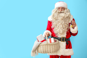 Santa Claus with Christmas bell, basket and presents on blue background