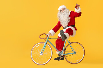 Santa Claus with Christmas bell and bicycle on yellow background
