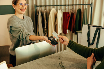 Friendly clothing store assistant taking a card payment