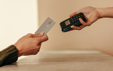 Woman's hand tapping a credit card on a contactless card reader