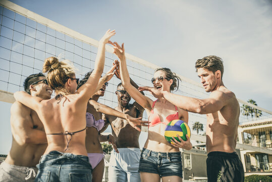 Storytelling image of a group of friends spending time in Santa Monica playing and having fun. Multiethnic young people from california reunited on the beach during a summer day.