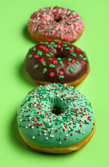 Tasty Christmas donuts on green background, closeup