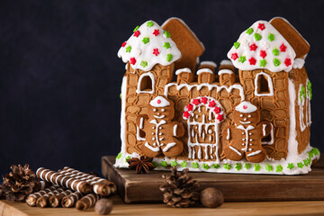 Wooden board with beautiful gingerbread house on blue background