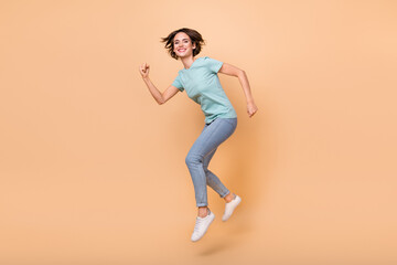 Fototapeta na wymiar Full size profile side photo of young lady run speed rush motion jump isolated over beige color background