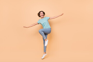 Fototapeta na wymiar Full body photo of young cheerful woman have fun jumper fly airplane isolated over beige color background