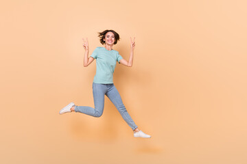 Fototapeta na wymiar Full size photo of young woman jump up show peace cool v-symbol isolated over beige color background