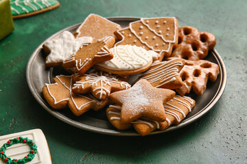 Plate with tasty Christmas cookies on green background