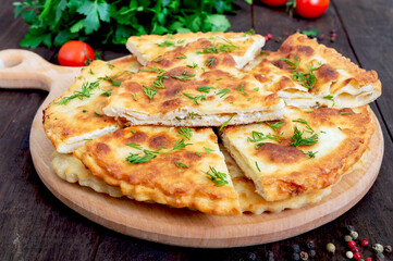 Khachapuri with cottage cheese and greens on a board. National Georgian dish.