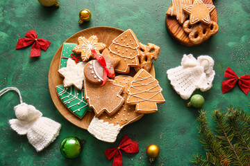 Plate with tasty gingerbread cookies and Christmas decorations on color background