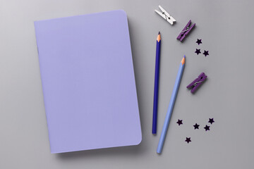 workplace on gray desk with violet blank notebook, pencils and glitter confetti. Color of the Year 2022 Very Peri. copy space