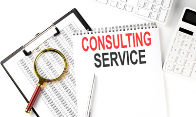 Office desk table with keyboard, notepad ,chart and calculator. Top view with text CONSULTING SERVICE