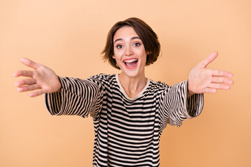 Photo of young cheerful girl open arms embrace welcome hospitable isolated over beige color...
