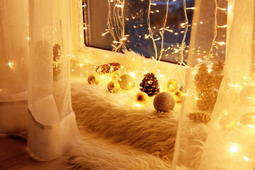 Beautiful Christmas decor and glowing lights near window in dark room, closeup