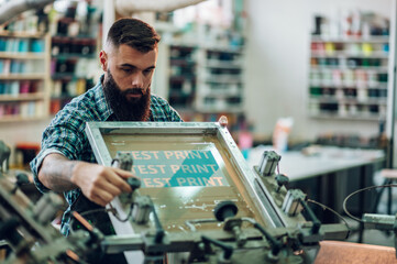 Male worker using printing machine in a workshop