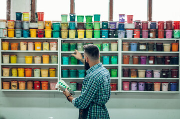 Male worker mixing colors for screen printing in a workshop