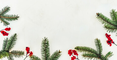 Christmas light background. Corner decorated with fir twigs and Christmas baubles. Red berries, candies, gifts, snowflake and fir cone. Top flat view with text copy-space.