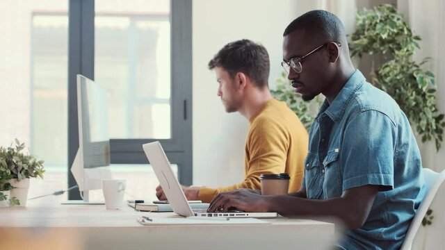 Video of two concentrated graphic designer working with computer in modern startup office.