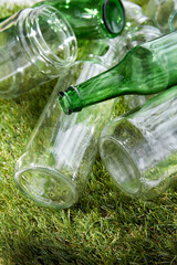 recycling, garbage disposal, environment and ecology concept - close up of empty used glass bottles and jars on grass